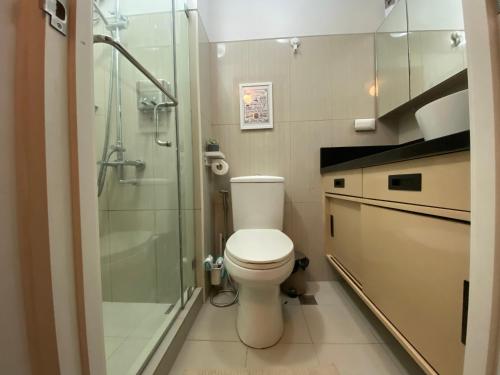 a bathroom with a toilet and a glass shower at Luxury Condo with Pool View at Shell Residences in Manila