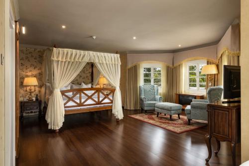 a bedroom with a canopy bed and a living room at The Westbury Palace in Nuwara Eliya