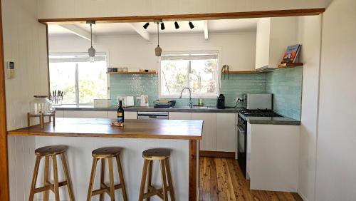 a kitchen with a counter and two bar stools at Selenas @ Culburra Beach in Culburra Beach
