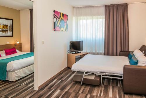 a hotel room with two beds and a tv at Mercure Agen Centre in Agen
