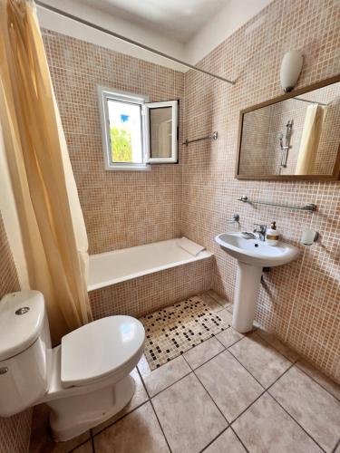 een badkamer met een toilet, een wastafel en een bad bij Pafia Sunbeach Townhouse in Paphos City