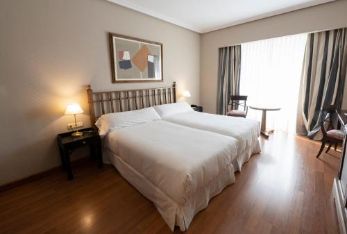 a bedroom with a large white bed and a window at Barceló León Conde Luna in León