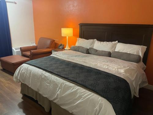 a bedroom with a large bed and a chair at B&J HOTEL AND APARTMENTS in Pecos