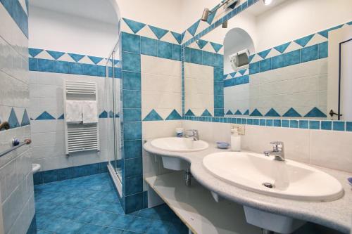 a blue and white bathroom with two sinks and a shower at Casa Augusto B&B in Capri