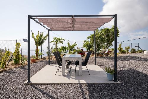 einen Tisch und Stühle unter einem Baldachin auf einer Terrasse in der Unterkunft La Casa del Barranco in Fasnia