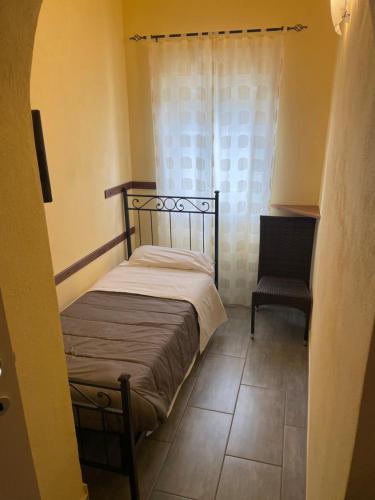 a small bedroom with a bed and a chair at Hotel La Torricella in Capalbio