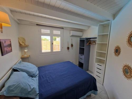 a bedroom with a blue bed and a window at Villa Eden, à 400 mètres de la plage du Souffleur in Port-Louis