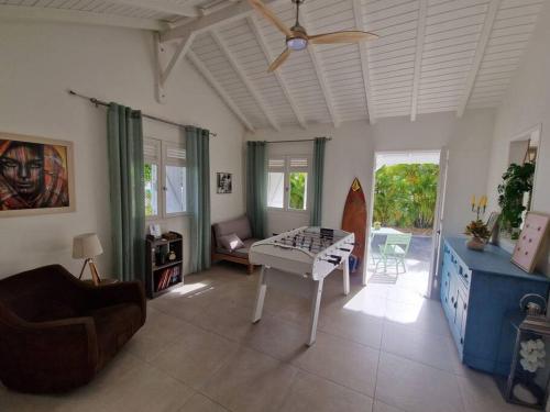 ein Wohnzimmer mit einem Deckenventilator und einem Tisch in der Unterkunft Villa Eden, à 400 mètres de la plage du Souffleur in Port-Louis