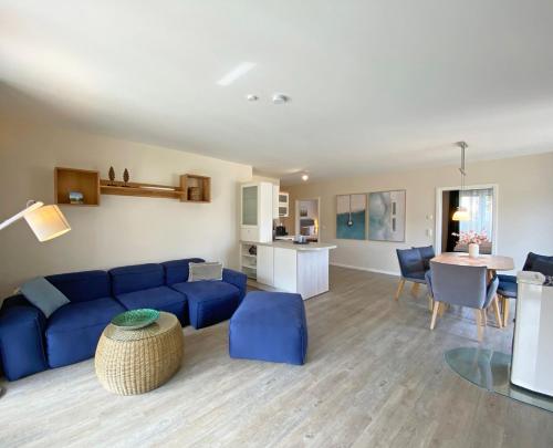 ein Wohnzimmer mit einem blauen Sofa und einem Tisch in der Unterkunft F Haus Sterntaucher Whg 01 mit Terrasse in Thiessow