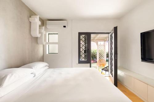 a white bedroom with a bed and a tv at Casa Doria by Burghesius in Rome