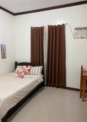 a bedroom with a bed and a window with curtains at Rachel's Bed and Breakfast Near Tagaytay in Silang