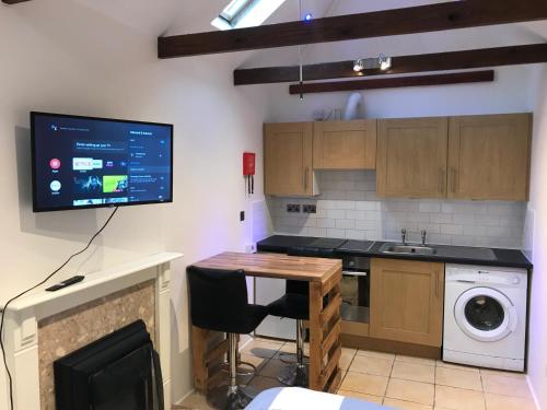 eine Küche mit einem Tisch und einem TV an der Wand in der Unterkunft Self contained annex in Bournemouth