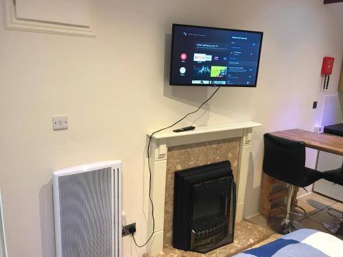 ein Wohnzimmer mit einem Kamin und einem Flachbild-TV an der Wand in der Unterkunft Self contained annex in Bournemouth