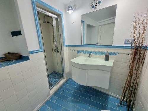un bagno blu e bianco con lavandino e doccia di Maridea - Medusa a Ponza