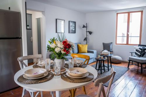 a kitchen and living room with a white table and chairs at Redbrick’s Bergerac, Au coeur du centre historique in Bergerac