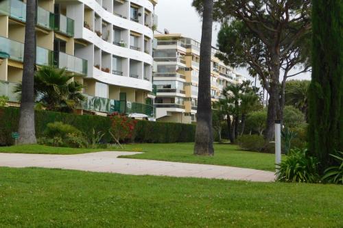 a large apartment building with a sidewalk and trees at Spacious 2-bedroom apartment in Egée residence with parking and air conditi in Cannes