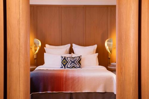 a bedroom with a bed with white sheets and pillows at Hôtel Vernet Champs Elysées Paris in Paris