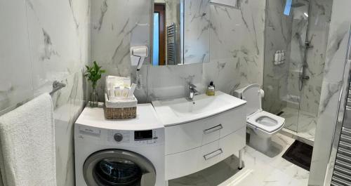 a white bathroom with a washing machine and a sink at Casa Teresa in Cluj-Napoca