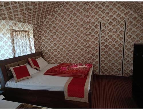 a bedroom with a bed with a red blanket on it at Sumeru Camp,Barkot in Barkot