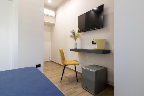 ein Schlafzimmer mit einem Bett und einem Stuhl sowie einem TV an der Wand in der Unterkunft Hispirya Rooms in Terracina