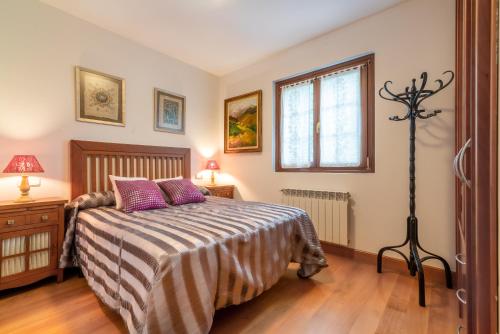 Un dormitorio con una cama con almohadas moradas y una ventana en Ortzimuga, en Huarte