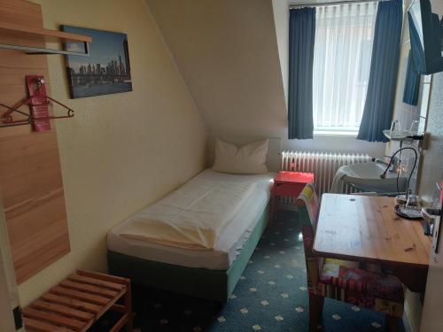 Kleines Zimmer mit einem Bett und einem Tisch in der Unterkunft Hotel Flora in Hannover