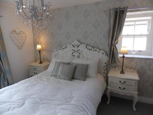 sypialnia z dużym białym łóżkiem z 2 stolikami nocnymi w obiekcie Waterloo Cottage w mieście Barnard Castle
