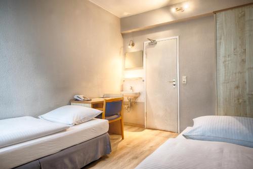 a room with two beds and a desk and a sink at enjoy hostel Berlin City West in Berlin