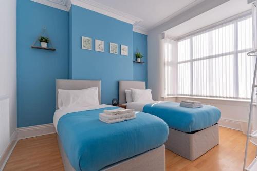 two beds in a room with blue walls at Edgbaston Stadium Luxury Contractor Accommodation in Birmingham