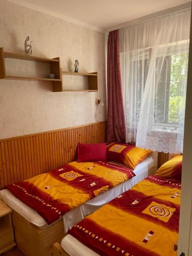 two beds sitting next to a window in a room at Rózsa nyaralóház in Balatonboglár