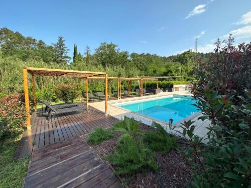 a swimming pool with a wooden deck and a bench next to it at Le Village Sarzana in Sarzana