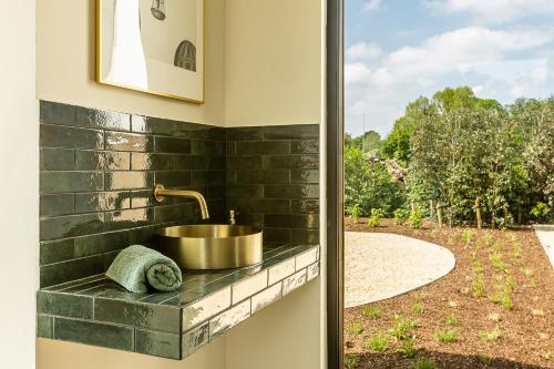 a bathroom with a sink and a view of a yard at Leie Villa II - by the river with sauna & jacuzzi in Deinze