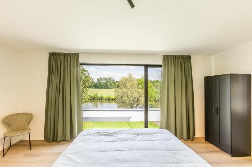 een slaapkamer met een bed en een groot raam bij Leie Villa II - by the river with sauna & jacuzzi in Deinze