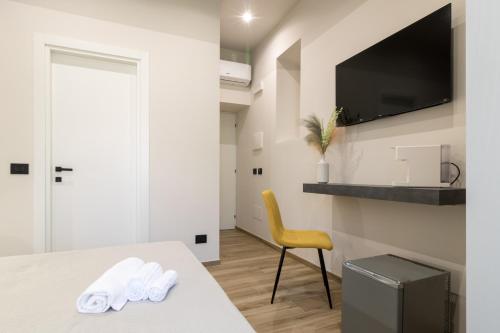 a white room with a table and a yellow chair at Hispirya Rooms in Terracina