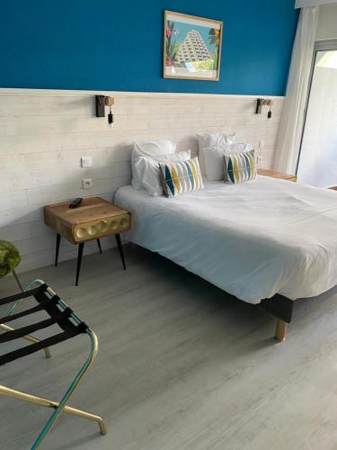 a bedroom with a large bed and a table at Hôtel Saint-Clair, côté Plage in La Grande Motte