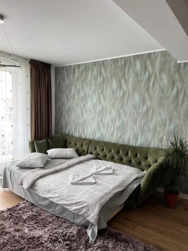 um quarto com uma cama grande e um sofá verde em Royal Class Apart Complex Uno Residence em Brasov