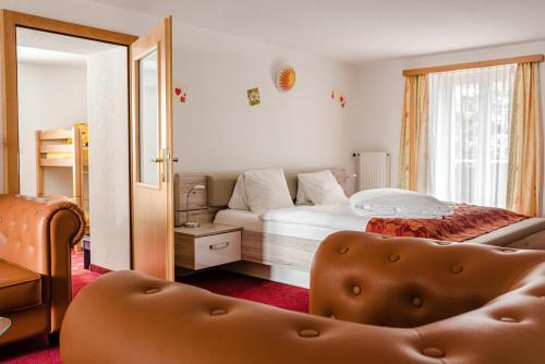 a bedroom with a bed and a chair and a mirror at Family Hotel & Spa Desirée in Grächen