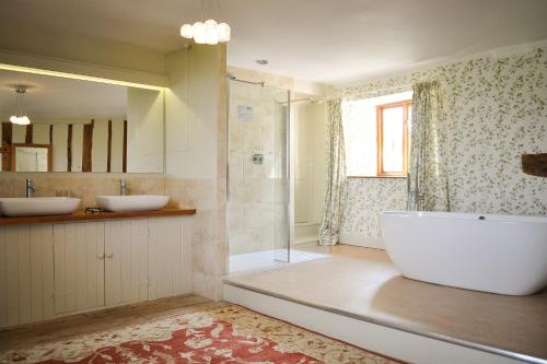 a bathroom with two sinks and a tub and a shower at Huntstile Organic Farm in Bridgwater