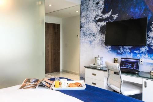 a hotel room with a bed with a desk and a tv at Wyndham Garden Brooklyn Sunset Park in Brooklyn