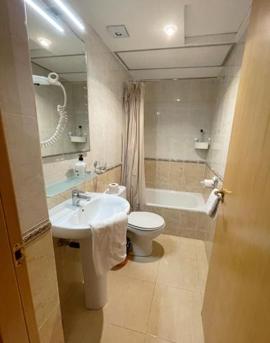 a bathroom with a sink and a toilet and a tub at Royal Inn Aparthotel in Lloret de Mar