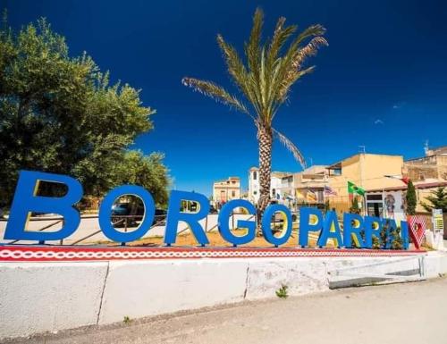 a sign for a resort with a palm tree in the background at Atelier House 69 in Trappeto