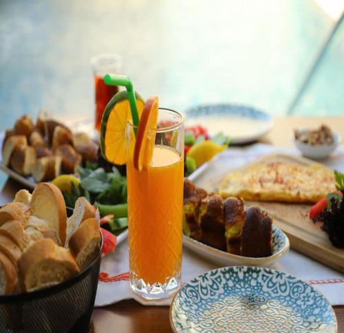 a table with a plate of food and a glass of orange juice at Grand Faik Hotel in Cesme