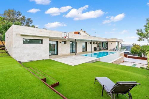 einen Außenblick auf ein Haus mit Rasen und Basketballkorb in der Unterkunft Villa de Lujo Welcs PDA 073 con Piscina y Vistas al Mar in Platja  d'Aro