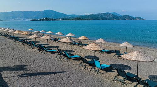 Uras Beach Hotel في فتحية: صف من الكراسي والمظلات على الشاطئ