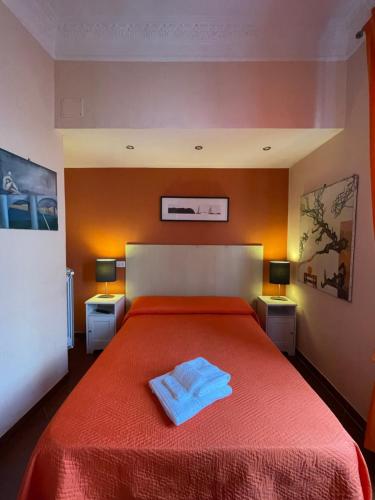 una camera da letto con un letto con copriletto rosso e 2 lampade; di Santa Bibiana a Roma