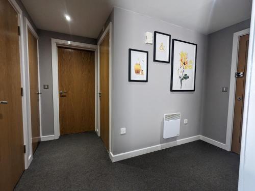 a hallway with a door and three pictures on the wall at Beautiful Modern Coventry City Centre Apartment in Coventry