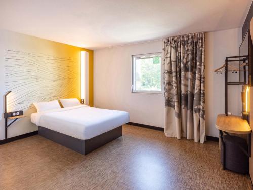 a hotel room with a bed and a window at B&B HOTEL Rennes Parc Expo Aéroport in Bruz