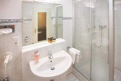 La salle de bains blanche est pourvue d'un lavabo et d'une douche. dans l'établissement Bad Emser Hof, à Bad Ems