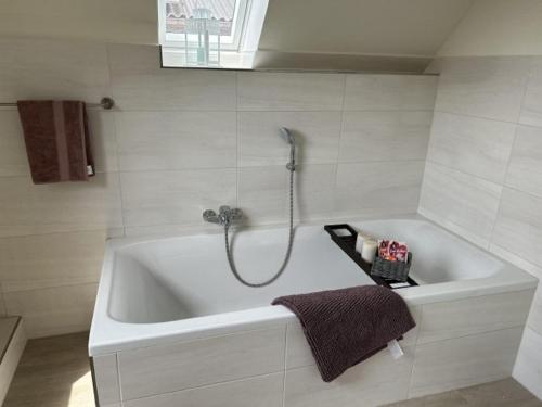 a white bath tub with a shower in a bathroom at Huus Marschkiek in Langenhorn