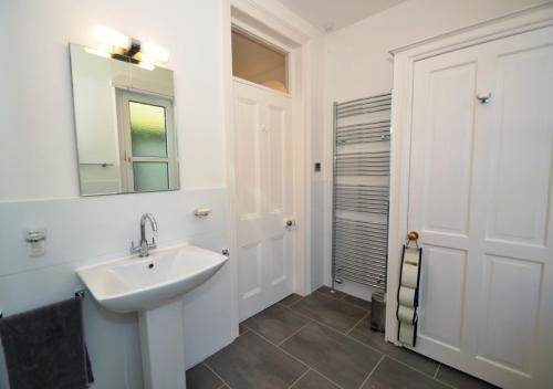 uma casa de banho branca com um lavatório e um espelho em 4 Thurlestone Court em Dartmouth
